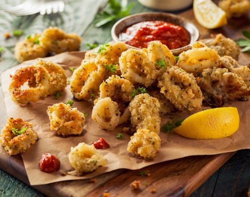 Fried calamari served on a plate with lemon wedges in a restaurant in Italy.