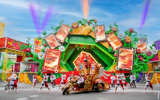 Colorful parade with performers and floats at Disneyland Paris.