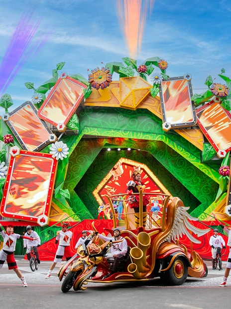 Colorful parade with performers and floats at Disneyland Paris.