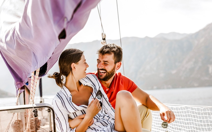 Couple enjoying a catamaran ride with mountain views in the background.