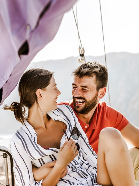 Couple enjoying a catamaran ride with mountain views in the background.