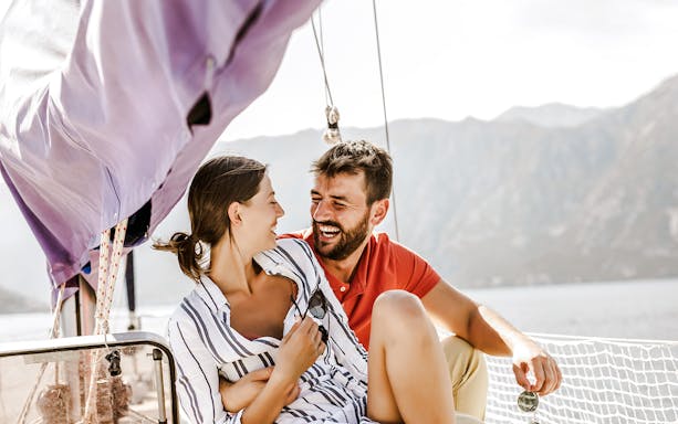 Couple enjoying a catamaran ride with mountain views in the background.