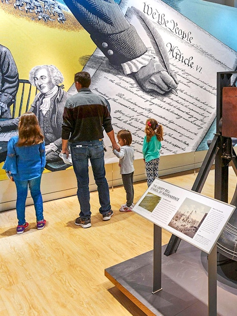 Liberty Bell replica and visitors at Museum of the Bible exhibit.