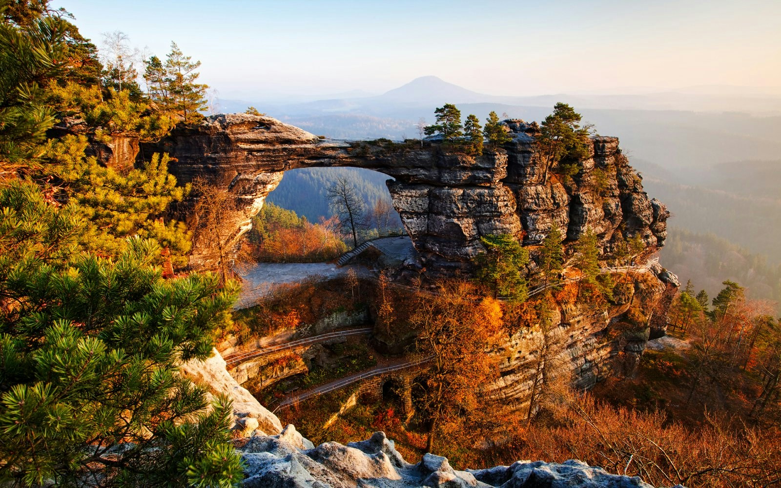 Pravcicka Gate rock formation in Bohemian Switzerland, surrounded by autumn trees.