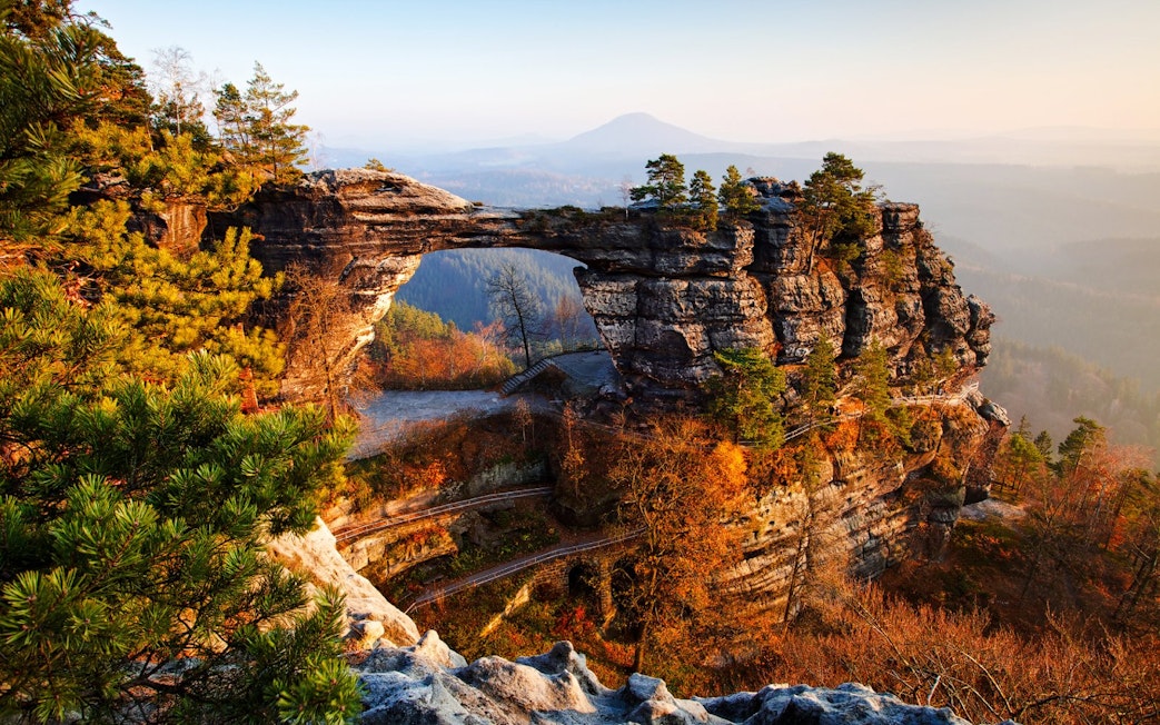 Pravcicka Gate rock formation in Bohemian Switzerland, surrounded by autumn trees.