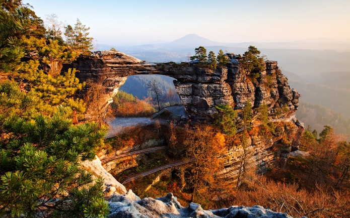 Pravcicka Gate rock formation in Bohemian Switzerland, surrounded by autumn trees.