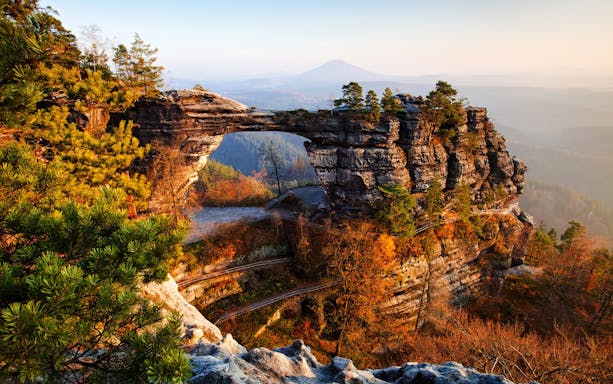 Pravcicka Gate rock formation in Bohemian Switzerland, surrounded by autumn trees.