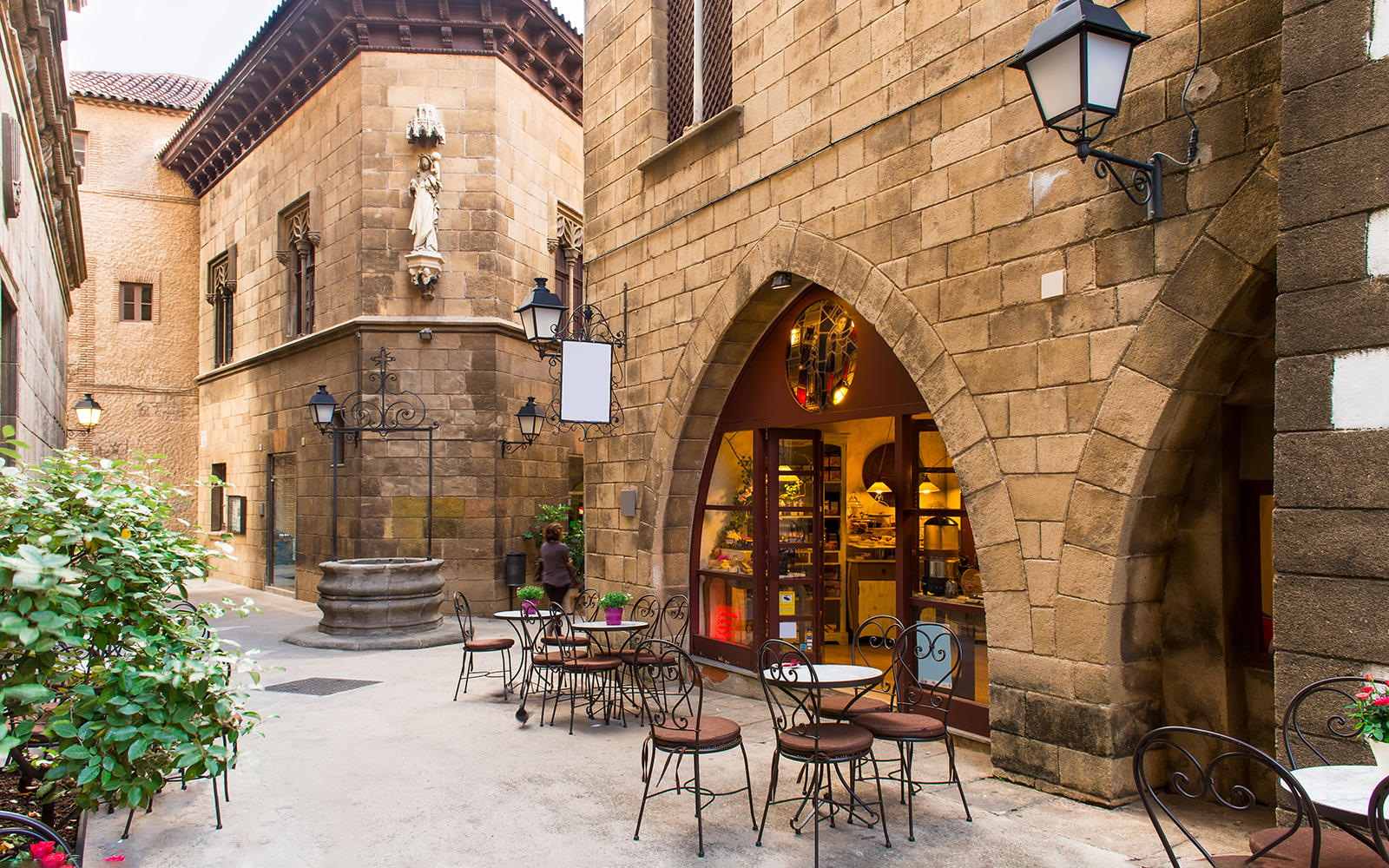 Courtyard cafe in Poble Espanyol, Barcelona, with stone buildings and outdoor seating.