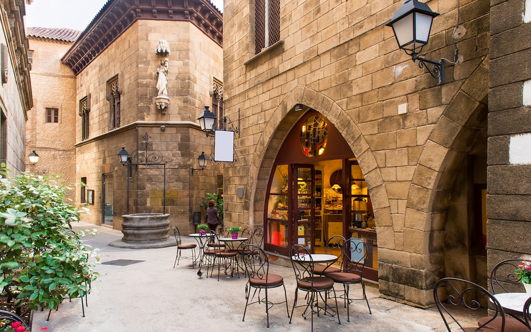 Courtyard cafe in Poble Espanyol, Barcelona, with stone buildings and outdoor seating.