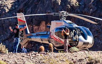 Helicopter landed at Grand Canyon West with tourists taking photos.