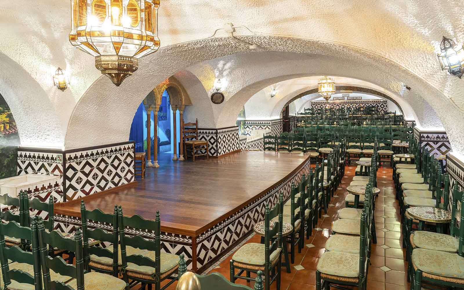 Tablao Cordobes interior with arched ceiling, wooden stage, and rows of chairs in Barcelona.