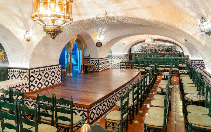 Tablao Cordobes interior with arched ceiling, wooden stage, and rows of chairs in Barcelona.