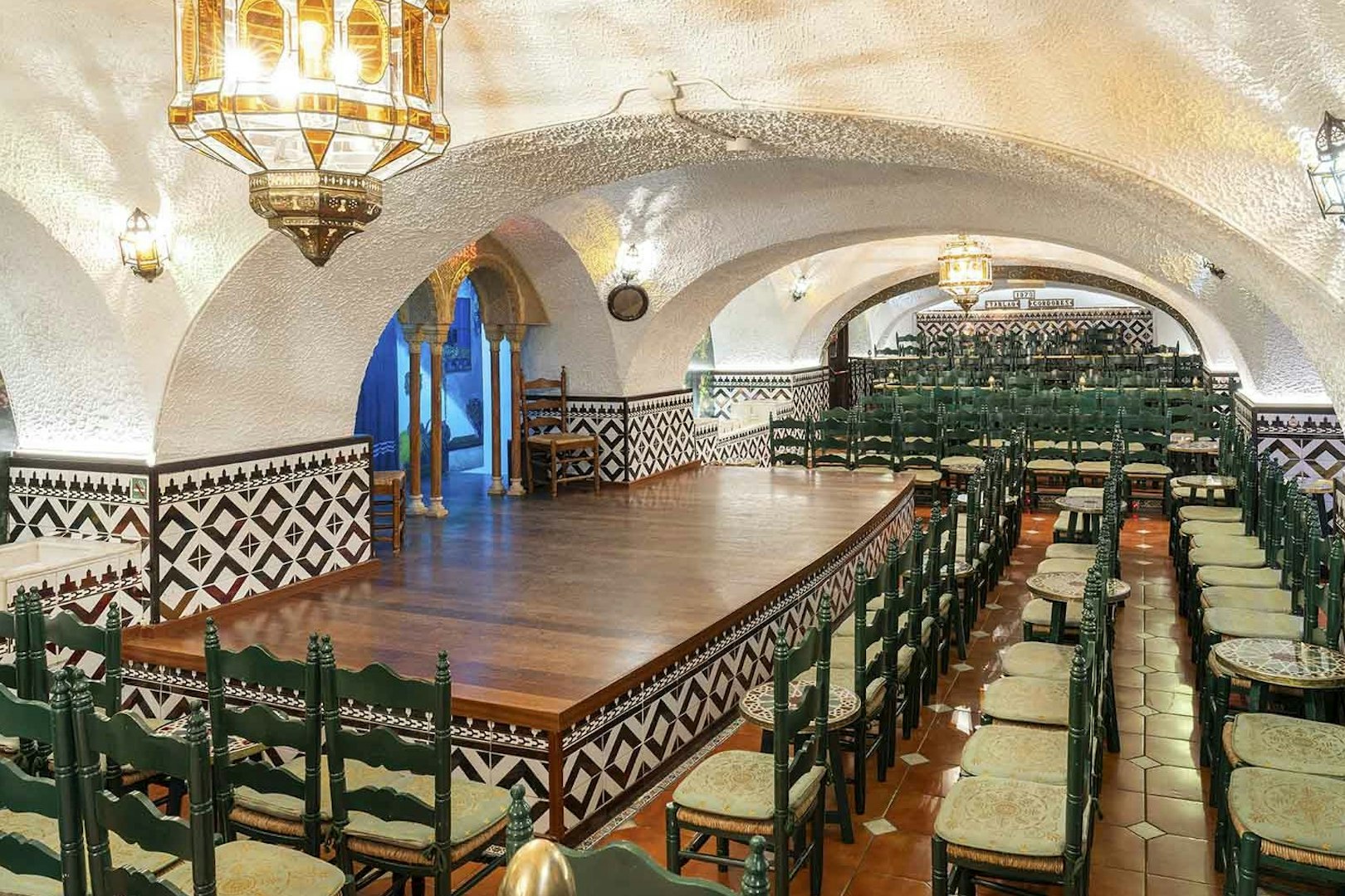 Tablao Cordobes interior with arched ceiling, wooden stage, and rows of chairs in Barcelona.