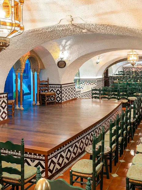 Tablao Cordobes interior with arched ceiling, wooden stage, and rows of chairs in Barcelona.