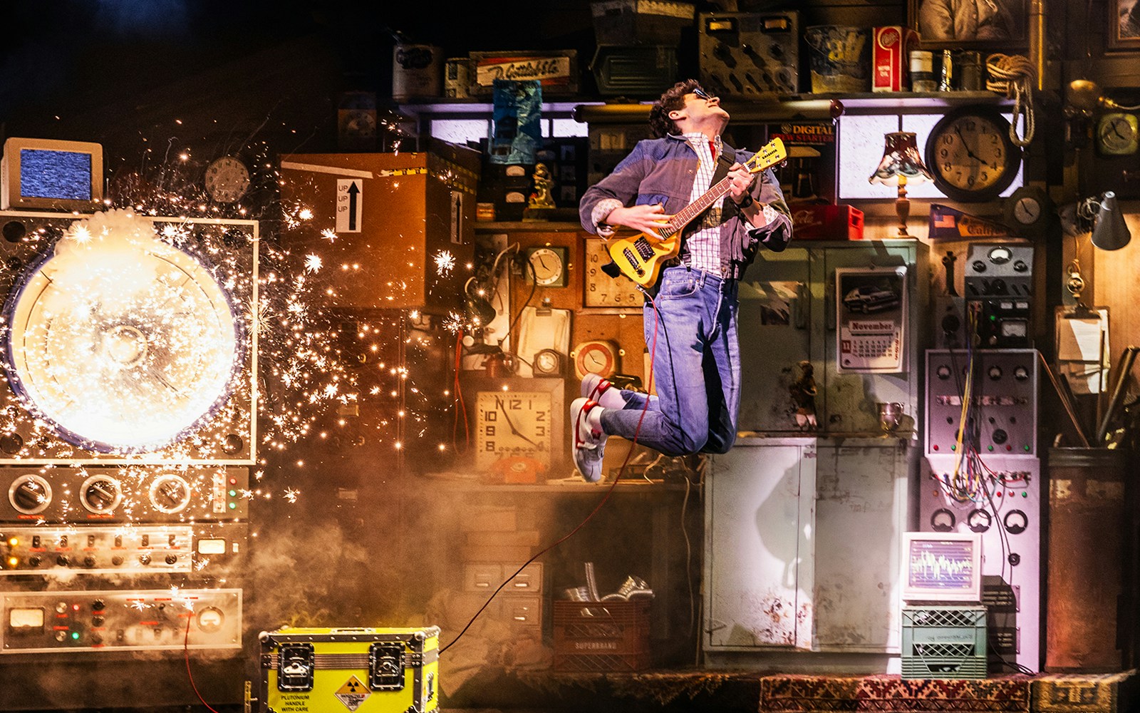 Performer playing guitar amid sparks in Back to the Future the Musical set.