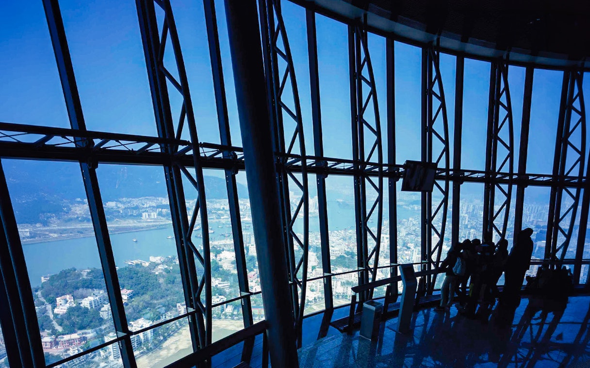 View from Macau Tower observation deck overlooking city and harbor.