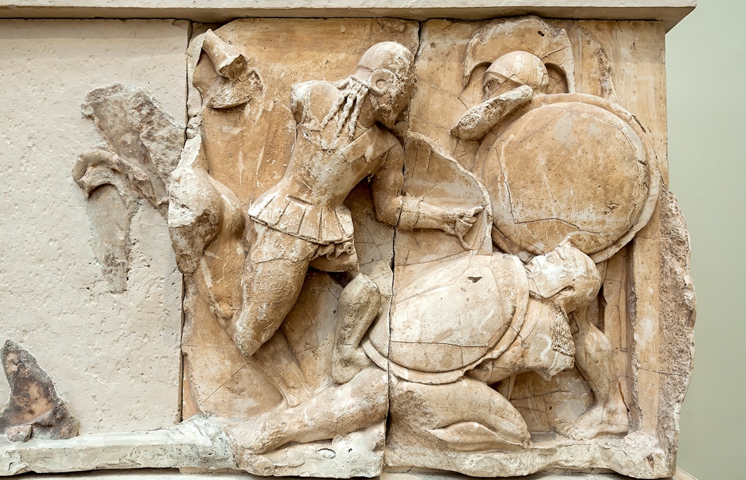 Ancient Greek relief depicting a battle scene with warriors in armor and shields.