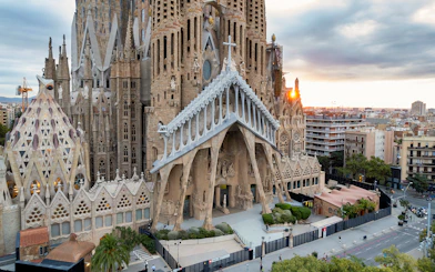 Sagrada Familia exterior with intricate facade in Barcelona, view of cityscape at sunset.