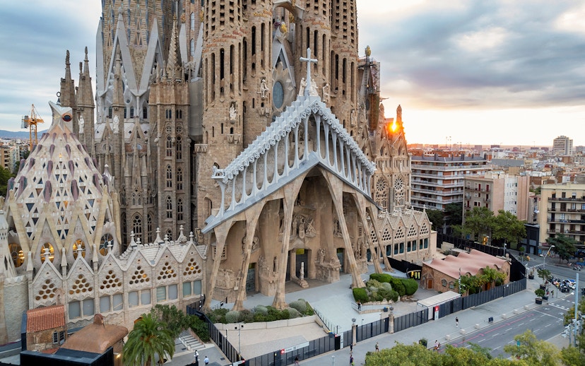 Sagrada Familia exterior with intricate facade in Barcelona, view of cityscape at sunset.