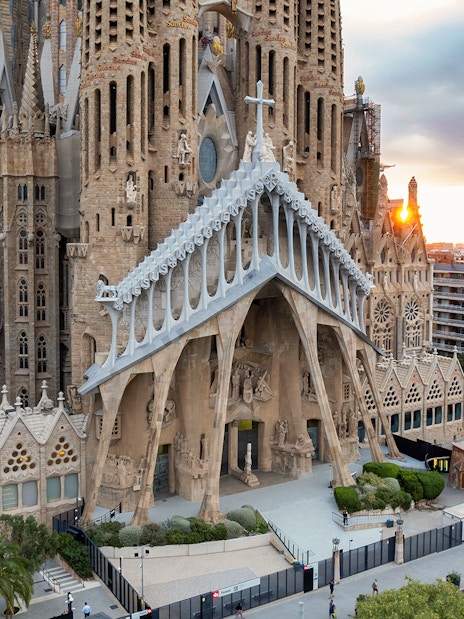 Sagrada Familia exterior with intricate facade in Barcelona, view of cityscape at sunset.