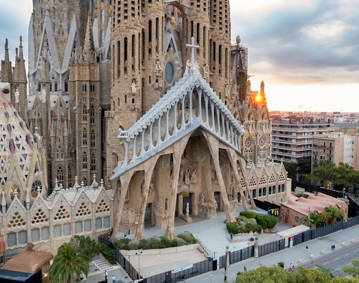 Sagrada Familia exterior with intricate facade in Barcelona, view of cityscape at sunset.