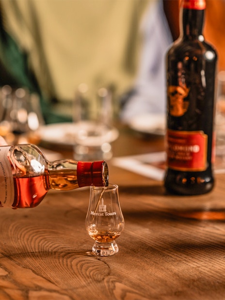 Pouring whiskey into a glass at Megget's Cellar tasting event.