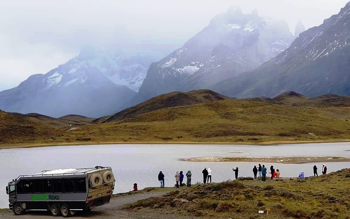 Tourists viewing mountains and lake in Torres del Paine National Park, Chile.