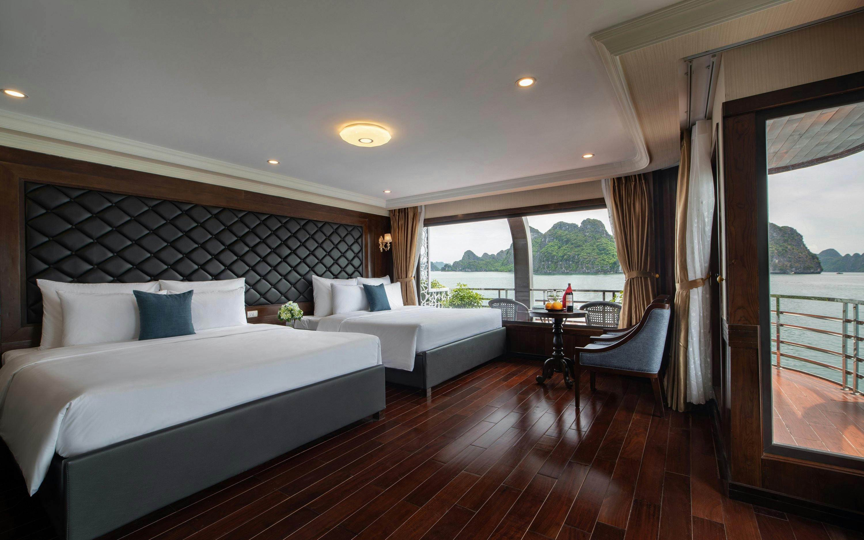 Cruise cabin with sea view in Lan Ha Bay, featuring two beds and a seating area.