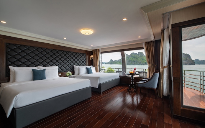 Cruise cabin with sea view in Lan Ha Bay, featuring two beds and a seating area.