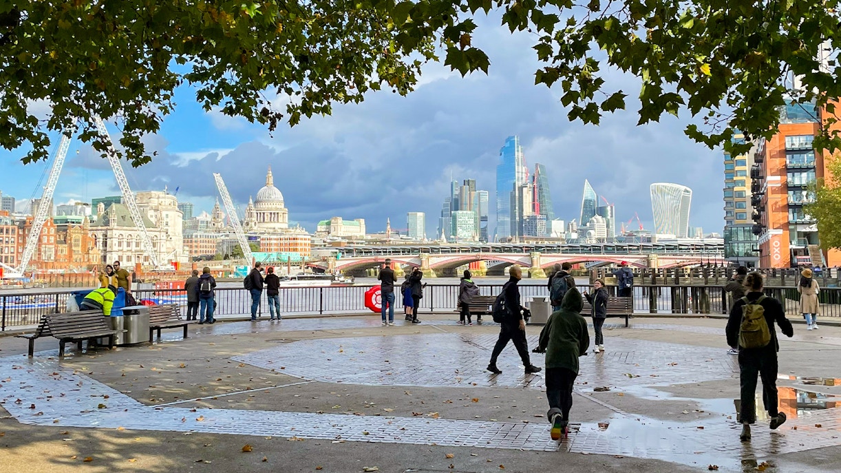 People walking on the South Bank with St Paul's Cathedral and The Shard in the London skyline.