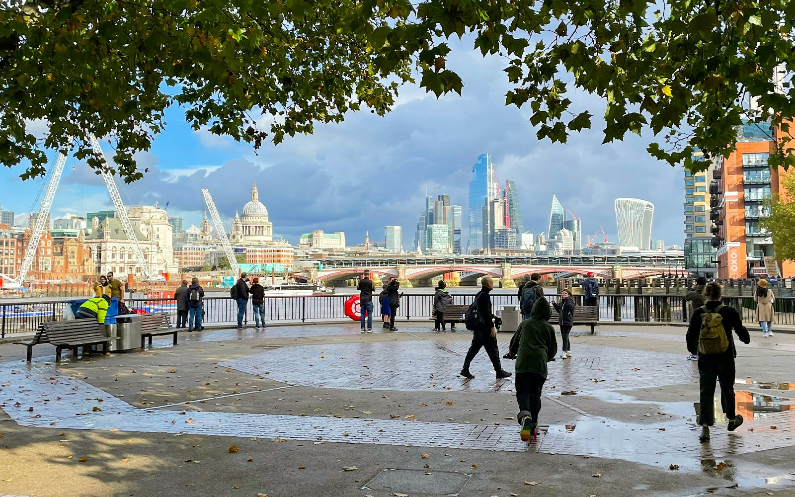 People walking on the South Bank with St Paul's Cathedral and The Shard in the London skyline.