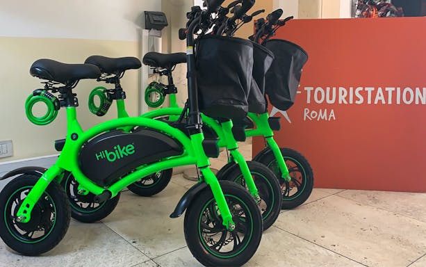 Green e-bikes at a rental station in Rome, Italy, for Baths of Caracalla tour.