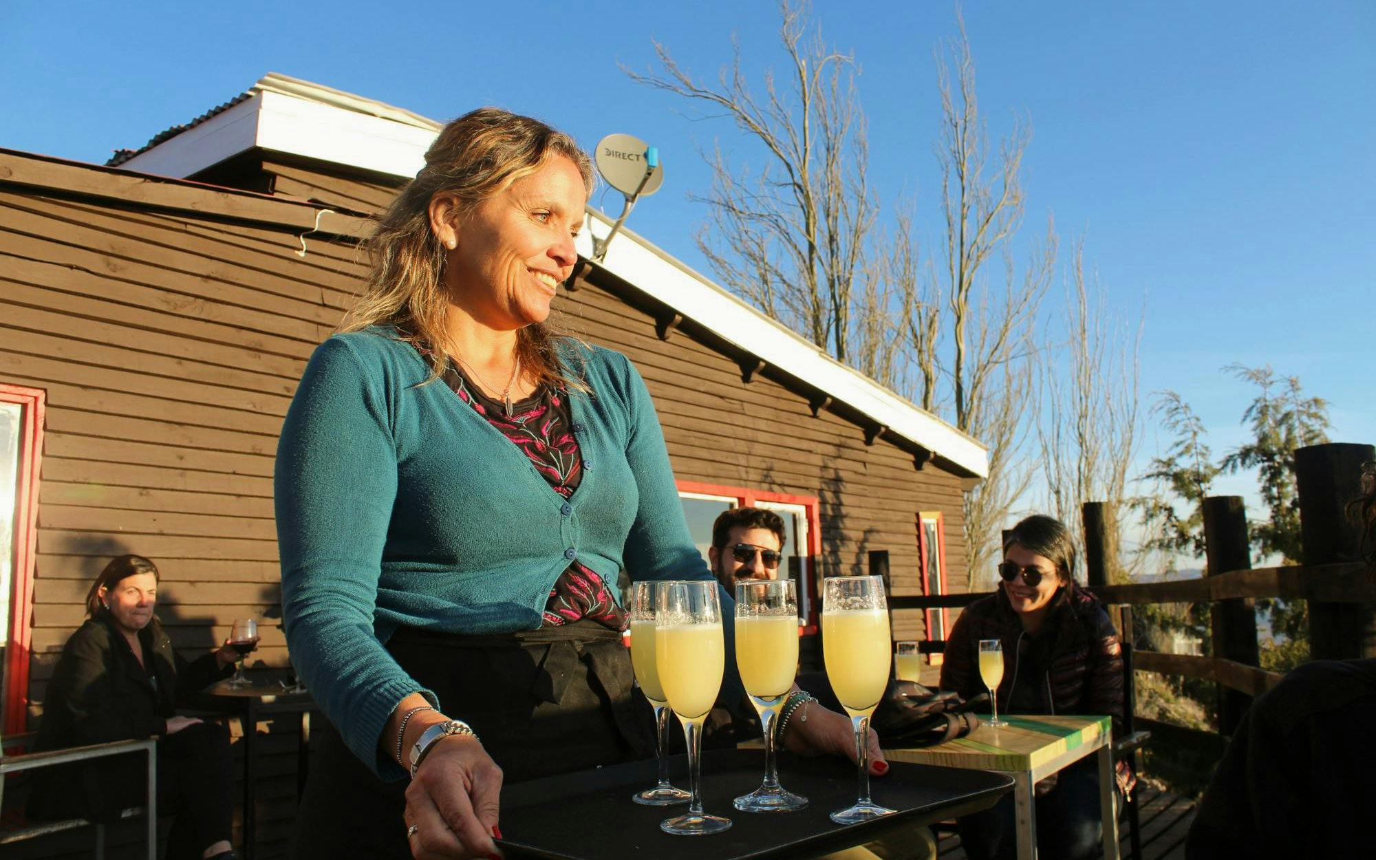 Waitress serving cocktails on a tray during sunset in the Andes Mountains.