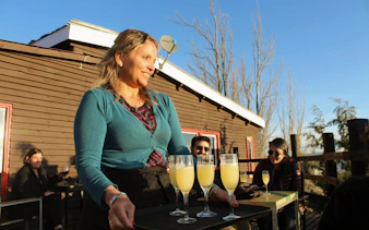 Waitress serving cocktails on a tray during sunset in the Andes Mountains.