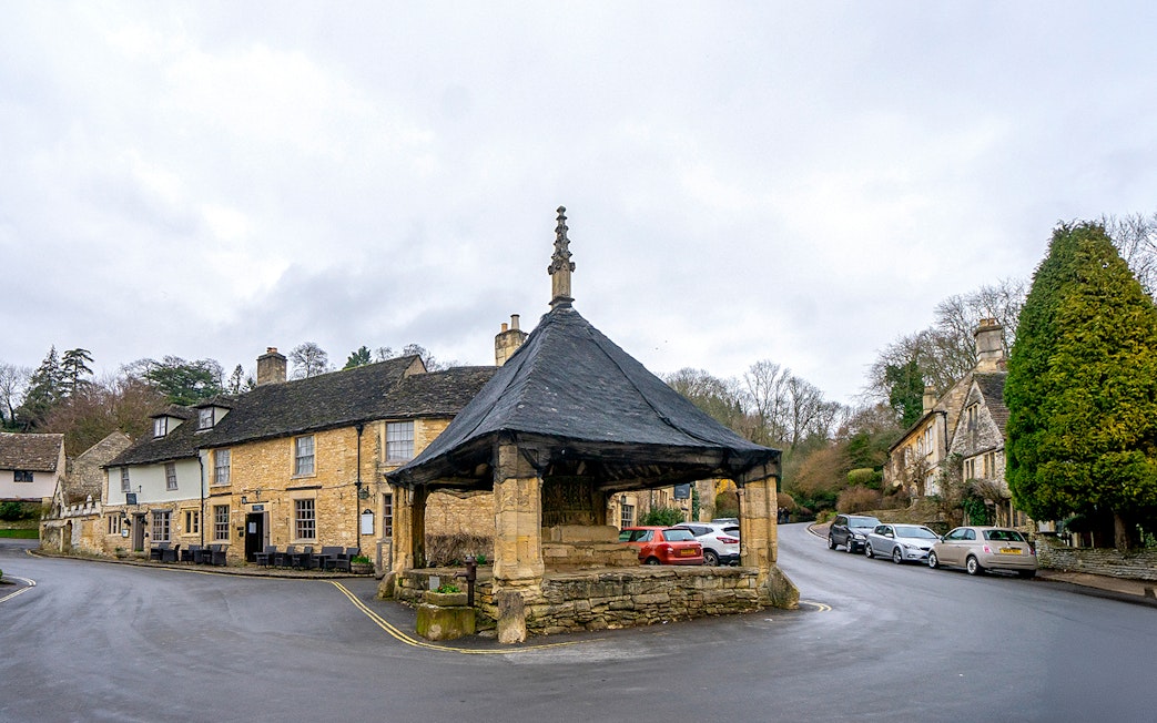 Cotswolds village scene with historic market hall and stone cottages.