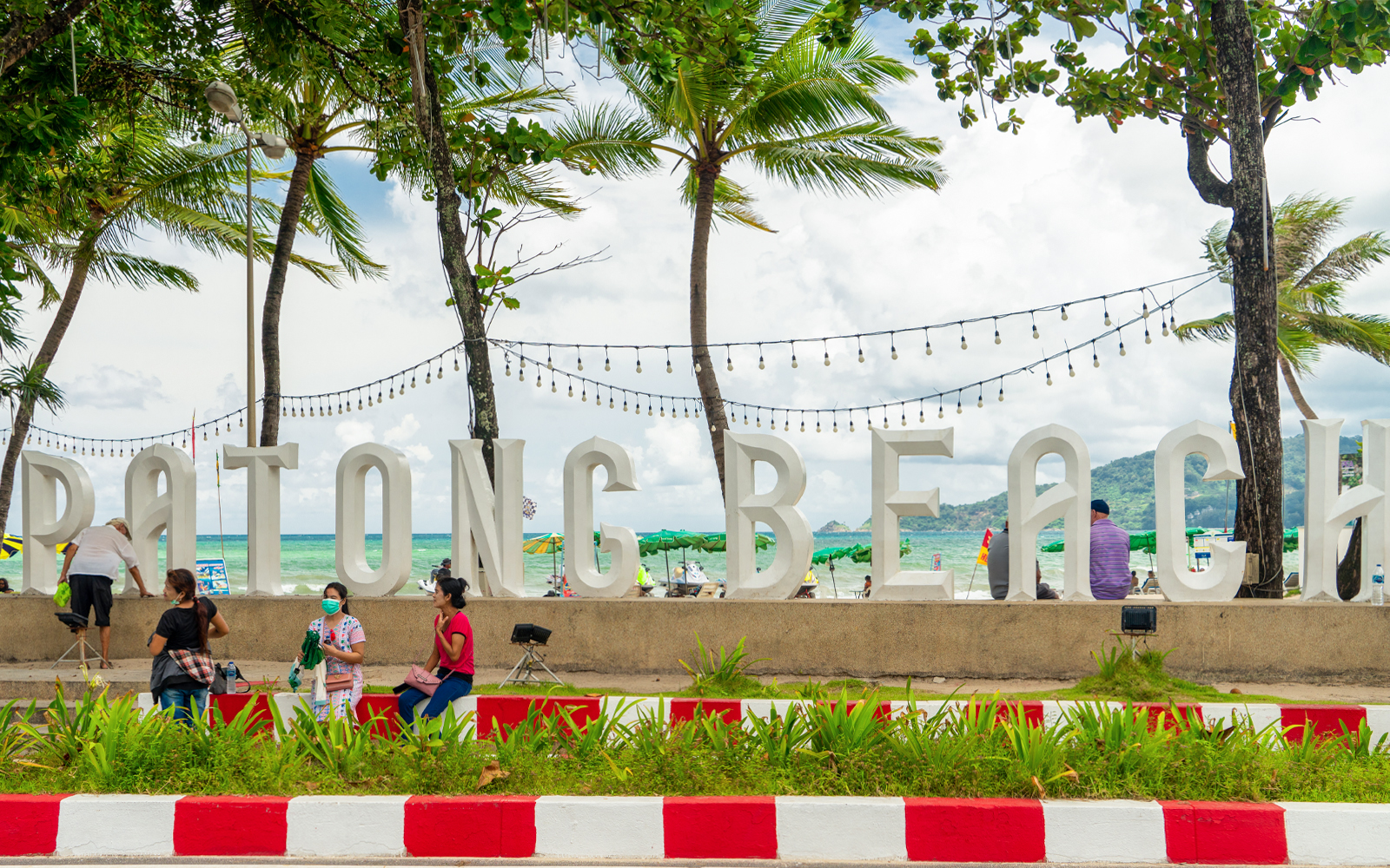 Patong Beach sign with people and palm trees, enroute to Phuket old town.