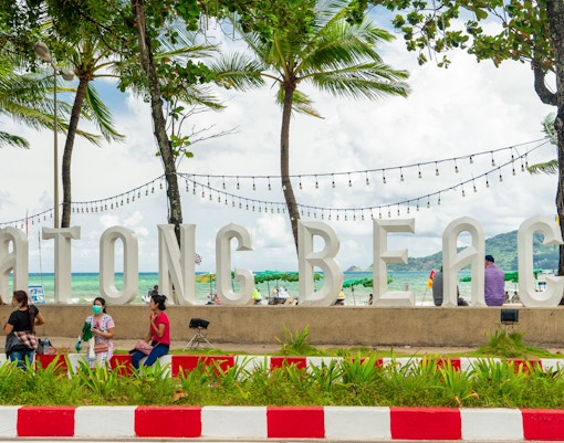 Patong Beach sign with people and palm trees, enroute to Phuket old town.