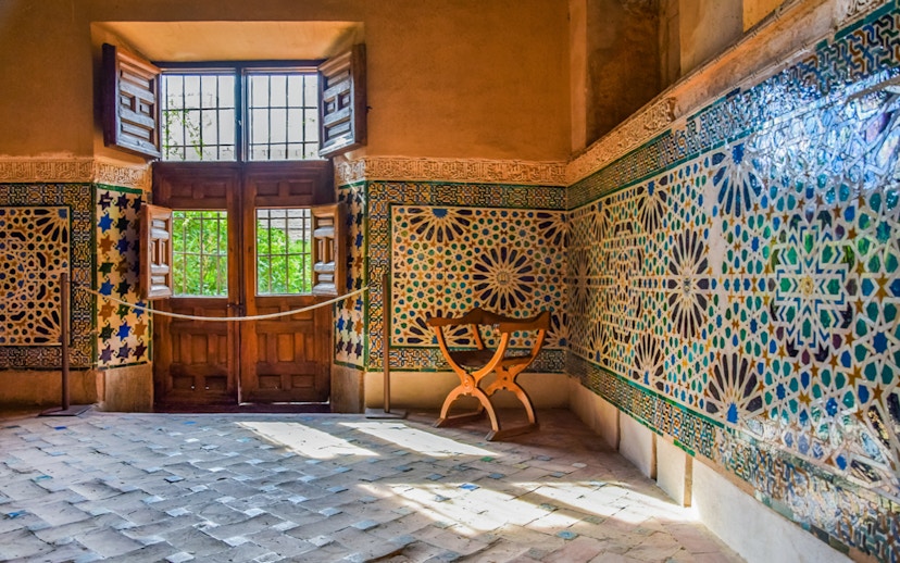 Alhambra interior with intricate mosaic tiles and wooden window, Granada, Spain.