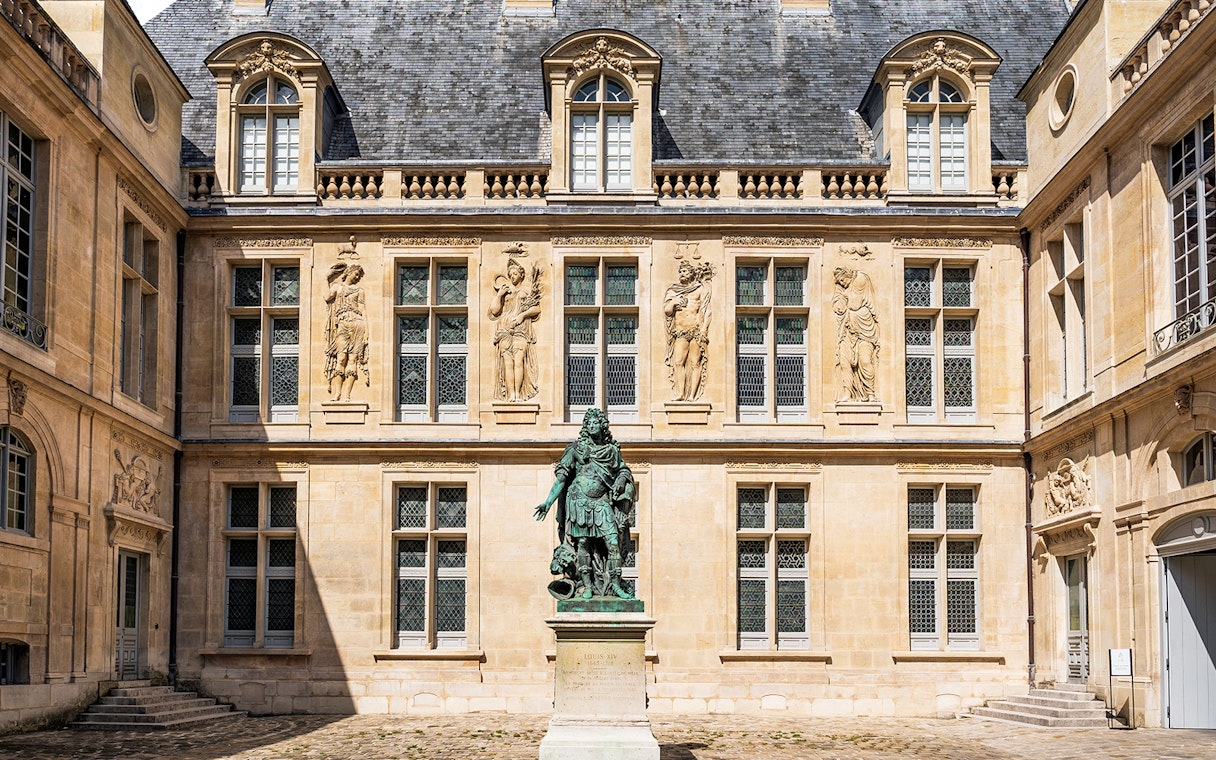 Courtyard of Carnavalet Museum in Paris with historic statue and ornate architecture.