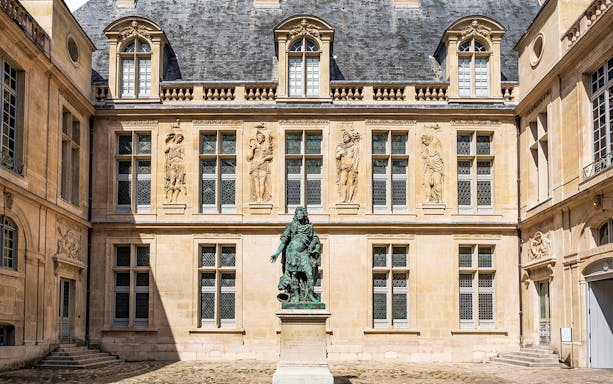 Courtyard of Carnavalet Museum in Paris with historic statue and ornate architecture.