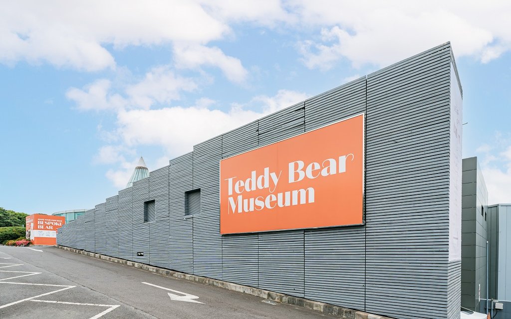 Teddy Bear Museum entrance with large orange sign on modern building.