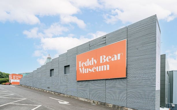 Teddy Bear Museum entrance with large orange sign on modern building.