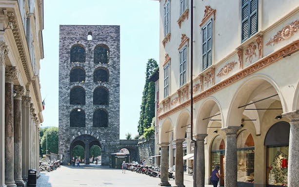 Como City stone tower and arched buildings on a sunny day.