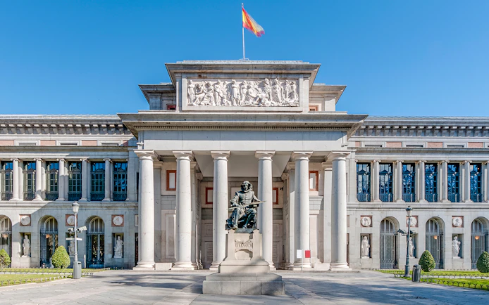 Facade of Prado Museum in Madrid with detailed neoclassical architecture and statue.