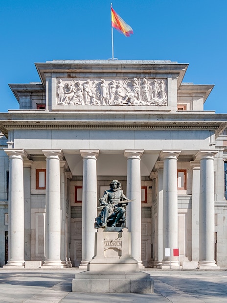 Facade of Prado Museum in Madrid with detailed neoclassical architecture and statue.