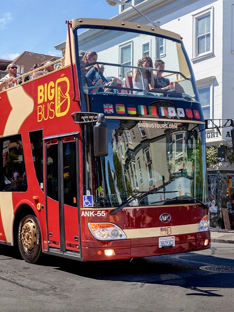 San Francisco hop-on hop-off tour bus driving through city streets.