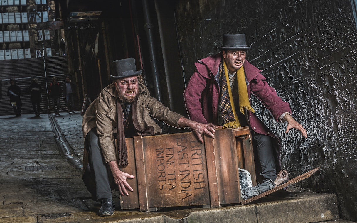 Actors in Victorian attire at Edinburgh Dungeon with a wooden crate.