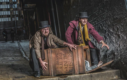 Actors in Victorian attire at Edinburgh Dungeon with a wooden crate.
