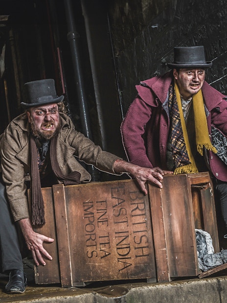 Actors in Victorian attire at Edinburgh Dungeon with a wooden crate.