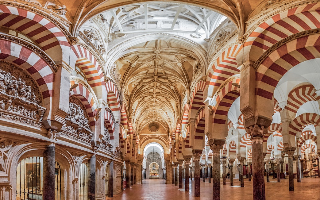 Interiors of the Cordoba Mosque-Cathedral prayer hall with red and white arches.